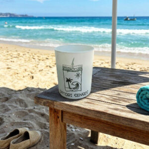 Vela aromática de playa tropical de cera de soja en una mesita de playa junto al mar